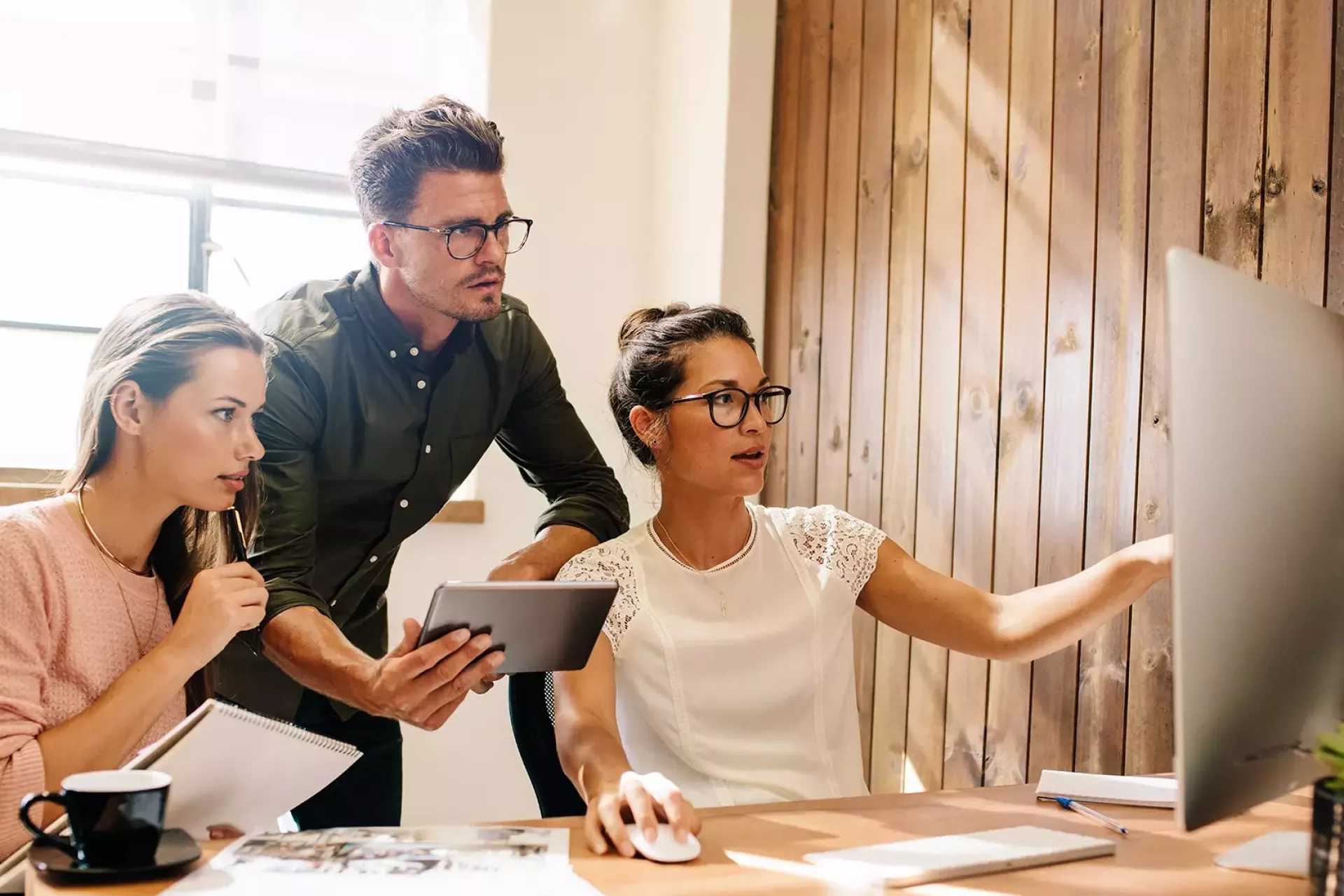 Drie mensen die samenwerken aan een computerproject.